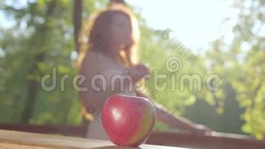特写<strong>一个红苹果</strong>和<strong>一个</strong>红发白种人女人在阳光下的背景。 白雪公主风格。 童话森林